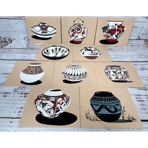 May include: A collection of nine prints featuring stylized illustrations of Native American pottery. The pottery designs include various shapes and patterns in black, red, and white on a tan background. The prints are arranged on a light wood surface.