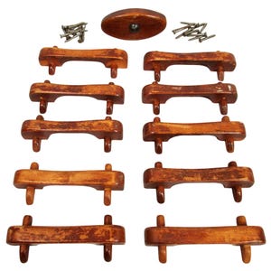 Può includere: Un set di maniglie per cassetti in legno e un pomello ovale abbinato, il tutto con una finitura marrone caldo. Il set include maniglie di varie dimensioni, ciascuna con due piccoli perni per il fissaggio e piccole viti.