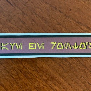 Könnte beinhalten: Ein Aufkleber mit weißem Rand und braunem Hintergrund. Der Aufkleber hat schwarzen Text, der "SKYVI EIV 70A/J0SI" lautet.