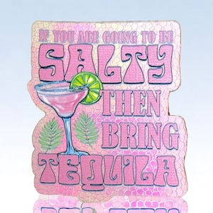 May include: Pink and blue wooden sign with the text "If you are going to be salty then bring tequila" and a pink margarita glass with a lime wedge.
