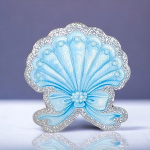 May include: A blue and silver glitter seashell with a bow. The seashell is a decorative item.
