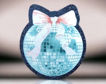 Puede incluir: Una bola de discoteca azul con un lazo rosa y blanco. La bola está hecha de un material brillante y tiene un borde negro.