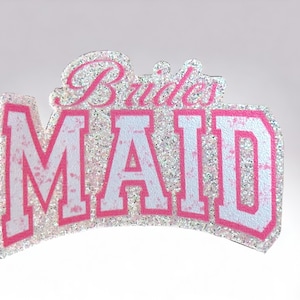 以下が含まれることがあります： 白い背景にピンクと白のグリッターで「Bride's Maid」と書かれたサイン