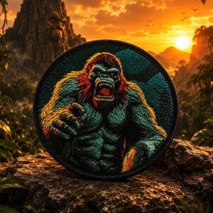 May include: Circular embroidered patch depicting a ferocious gorilla with red and green fur, open mouth, and bared teeth. The patch has a black border. The background shows a jungle scene with a sunset.