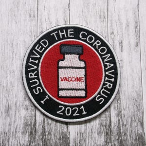 May include: A black and white embroidered patch with a red circle in the center. The circle has a white vial with the word "VACCINE" on it. The text around the circle reads "I SURVIVED THE CORONAVIRUS 2021".
