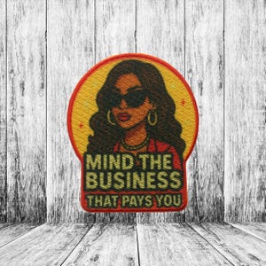 May include: Embroidered patch featuring a stylish woman with sunglasses, hoop earrings, and a red jacket, set against a yellow circle with a red border. The text "MIND THE BUSINESS THAT PAYS YOU" is displayed below the image.