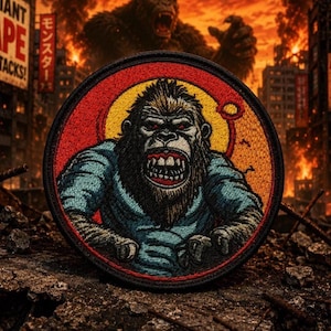 May include: Round patch depicting a gorilla with an angry expression, wearing a blue shirt. The patch has a red and yellow circular border. The background shows a city in flames with the words "GIANT APE ATTACKS!"