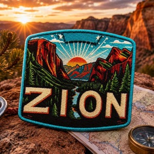 May include: Embroidered patch featuring a scenic landscape with the word "ZION" in bold letters. The patch showcases a mountain range, a river, and a sunrise, framed by a turquoise border. The patch is placed on a map with a compass.