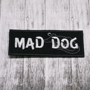 Può includere: Toppa ricamata nera con testo bianco che recita "MAD DOG" e una silhouette di cane stilizzata.