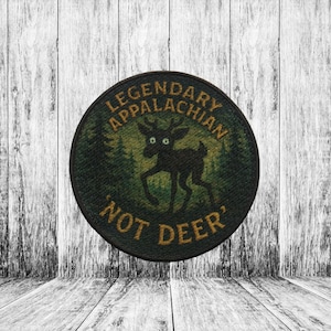 May include: A round, embroidered patch with the text "LEGENDARY APPALACHIAN" and "NOT DEER" in gold lettering. The patch features a silhouette of a deer with large eyes against a green forest background.
