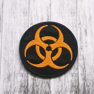 May include: A black circular patch with an orange biohazard symbol embroidered on it.
