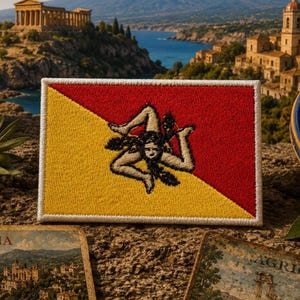 May include: A rectangular embroidered patch featuring the flag of Sicily, divided diagonally into red and yellow sections. In the center, a black triskelion emblem depicts three bent legs radiating from a central winged head with wheat stalks.