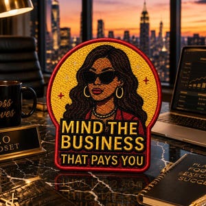 May include: A circular embroidered patch with a red border featuring a stylized illustration of a person with long dark hair, gold hoop earrings, and black sunglasses. The text reads MIND THE BUSINESS THAT PAYS YOU in bold yellow letters.