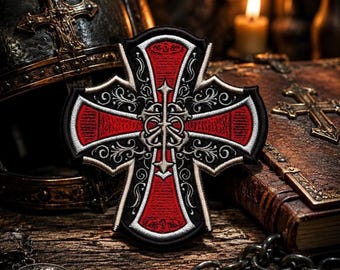 Peut inclure: Écusson brodé représentant une croix rouge avec des détails noirs et blancs ornés. Le patch a une bordure noire. L'image comprend une surface en bois, un casque et une bougie allumée. Le design de la croix est complexe et détaillé.