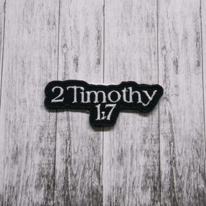 May include: Black and white embroidered patch with the text "2 Timothy 1:7" in a white font.