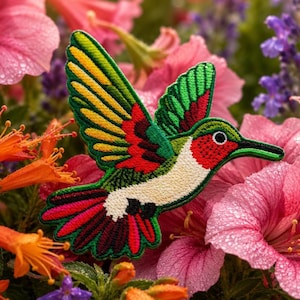 May include: An embroidered patch shaped like a hummingbird in flight. The bird features a vibrant colour palette of green, yellow, red, and white thread, with a distinct red throat patch, a long thin black beak, and a dark eye, showcasing detailed stitching.