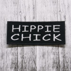 Könnte beinhalten: Schwarzer Stoff-Patch mit weiß gesticktem Text, der "HIPPIE CHICK" lautet.