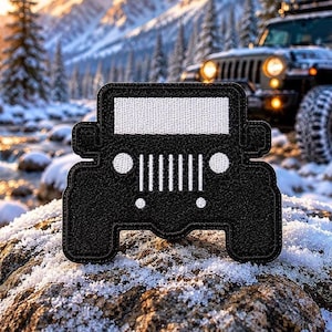 Può includere: Una toppa nera a forma di Jeep. La toppa ha una parte superiore rettangolare bianca e un design a griglia bianco. Lo sfondo mostra una Jeep e un paesaggio montano innevato.