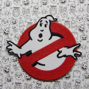 Peut inclure: Un fantôme blanc avec un cercle rouge et une ligne diagonale qui le traverse. Le fantôme a une expression surprise et les bras tendus. Le cercle a un contour noir et la ligne est rouge. L'arrière-plan est un motif blanc et noir de symboles d'Halloween.