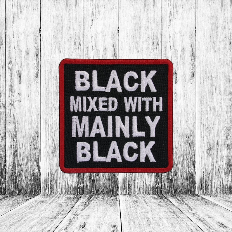 May include: A square embroidered patch with a black background and a thin red border. The patch features white embroidered text that reads: BLACK MIXED WITH MAINLY BLACK. The lettering is arranged in four lines, centered within the square frame.