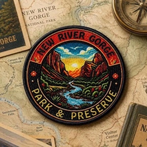May include: A circular embroidered patch featuring a landscape of the New River Gorge with a winding blue river, green trees, and orange cliffs under a yellow sunset. The black border contains the text NEW RIVER GORGE PARK & PRESERVE.