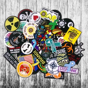 May include: A collection of embroidered patches in various shapes and sizes. Designs include a skull and crossbones, a sunflower, an American flag, and text such as "Be Brave" and "Find Your Patience".