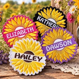 Könnte beinhalten: Vier kreisförmige, bestickte Sonnenblumen-Aufnäher mit gewelltem Rand. Jeder Aufnäher zeigt ein gelbes Sonnenblumenmotiv mit einem zentralen Banner, auf dem die Namen Elizabeth, Katherine, Dawson und Hailey in fetter, großgeschriebener Schrift stehen.