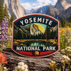 May include: Embroidered patch featuring a scenic view of Yosemite National Park. The patch displays a mountain range, lake, and trees under a yellow sun. The text "YOSEMITE NATIONAL PARK" is arched across the top and bottom in white.