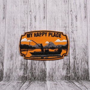 May include: Orange embroidered patch with a silhouette of a person fishing from a boat on a lake. The text "MY HAPPY PLACE" is above the scene.