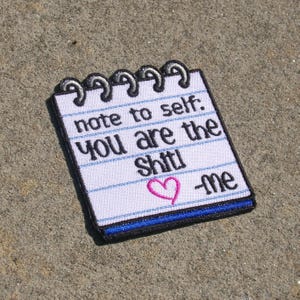 Pode incluir: Remendo bordado em forma de bloco de notas com o texto "note to self: YOU are the Shit! ❤️ -me". O remendo tem um fundo branco com linhas azuis e uma borda preta.