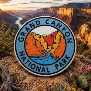 May include: Embroidered patch featuring the Grand Canyon National Park. The patch is circular with a blue border and the words "GRAND CANYON NATIONAL PARK" in white. The center depicts a colorful canyon scene.