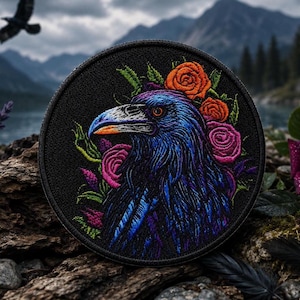 May include: A circular embroidered patch featuring a detailed raven head in shades of blue and purple, surrounded by vibrant orange and pink roses with green leaves, all set against a solid black background with a stitched border.