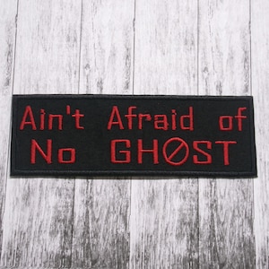 Könnte beinhalten: Schwarzer gestickter Aufnäher mit rotem Text, der "Ain't Afraid of No GHOST" lautet, mit einem roten Kreis mit einem diagonalen Strich durch.