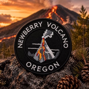 Może przedstawiać: Czarna okrągła naszywka z wulkanem w erupcji z czerwoną i pomarańczową lawą, szarym dymem i napisem "Newberry Volcano Oregon" w kolorze białym. Naszywka jest umieszczona na tle wulkanu i zachodu słońca.