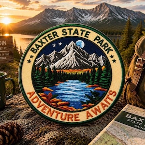 May include: Embroidered patch with a mountain and lake scene, the text "BAXTER STATE PARK" and "ADVENTURE AWAITS". The patch is round with a cream-colored border, green and blue details, and a night sky with stars and a moon. A green enamel mug and a backpack are in the background.