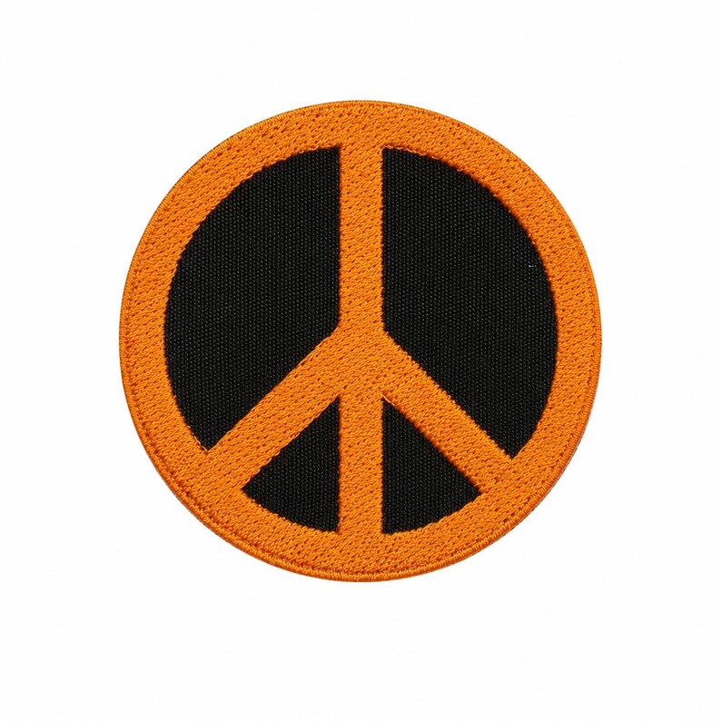 May include: Round patch featuring a peace symbol. The symbol is a bright orange color and is set against a black background. The patch has an orange border and is likely made of fabric.