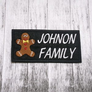 May include: Black embroidered patch with a gingerbread man and the text "JOHNON FAMILY" in white.