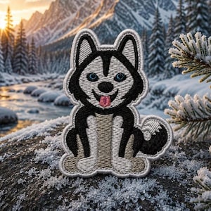 May include: An embroidered patch featuring a stylized husky dog with black and white fur, bright blue eyes, and a pink tongue sticking out. The design is outlined in a thick white border, showcasing detailed stitching throughout the entire figure.