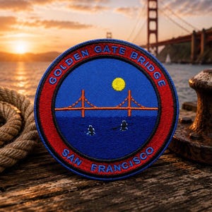 Peut inclure: Écusson brodé représentant le Golden Gate Bridge à San Francisco. L'écusson a un fond bleu avec un soleil jaune et le pont en orange. Le texte "GOLDEN GATE BRIDGE" et "SAN FRANCISCO" sont en bleu.