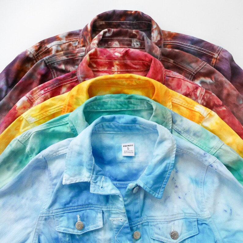 May include: A stack of six denim jackets in various tie-dye patterns, including blue, green, yellow, red, and brown. The top jacket has a "POP-MINT" label with a size "S" on the inside.