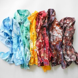 May include: A rainbow of tie-dye denim jackets in blue, green, yellow, red, and brown. The jackets are arranged in a row, with the blue jacket on the left and the brown jacket on the right.