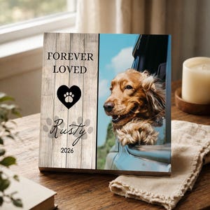 May include: A rectangular wooden plaque featuring a vertical split design. The left side has a light wood grain pattern with the text FOREVER LOVED, a black heart with a paw print, the name Rusty, and the year 2026. The right side shows a dog.