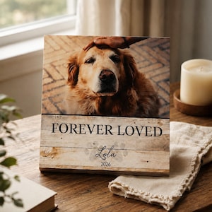 May include: A rectangular wooden plaque featuring a photograph of a golden dog being petted. The lower section has a light wood grain finish with the text FOREVER LOVED, the name Lola in script, and the year 2026 printed in black ink.