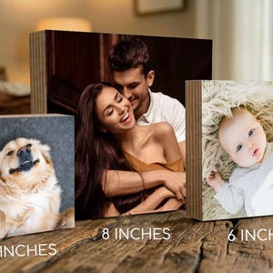 three different sizes of wooden blocks, each containing a different type of photo: a close-up of a dog, a couple embracing, and a baby lying down.