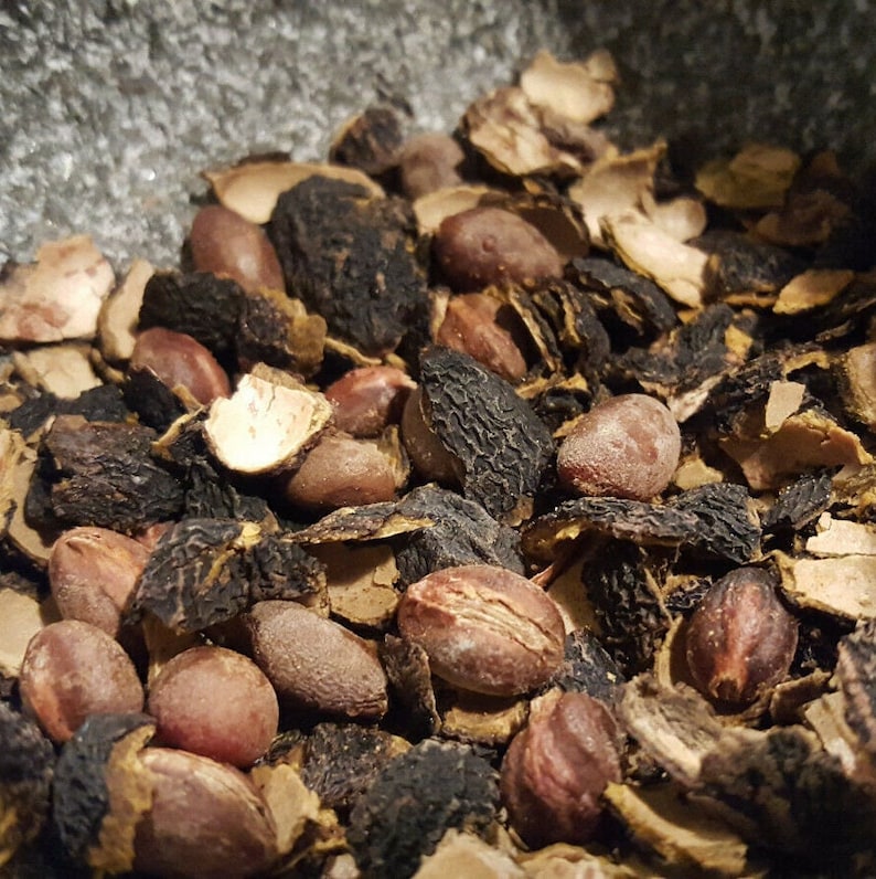 Pode incluir: Close-up de um monte de caro&ccedil;os de fruta secos, castanhos e pretos. Os caro&ccedil;os est&atilde;o partidos, revelando as sementes no interior.