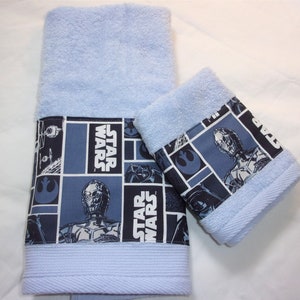 May include: A set of two blue towels with a Star Wars themed border. The border features a collage of Star Wars characters and the words "Star Wars".