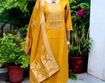 May include: A mustard yellow kurta with gold embroidery and a matching dupatta. The dupatta has a floral pattern with gold accents. The kurta is worn by a mannequin.