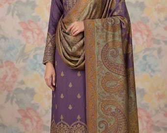 May include: A woman in a purple salwar kameez outfit with gold embroidery. The ensemble comprises a long-sleeved tunic, matching trousers, and a paisley-patterned shawl. The backdrop displays a floral design.