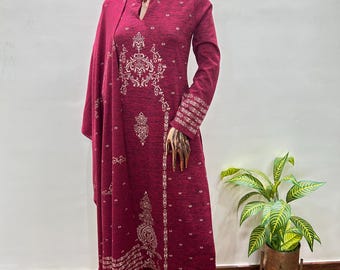 May include: A deep burgundy outfit comprising a tunic, trousers, and shawl, all adorned with white embroidery. The tunic has a mandarin collar and detailed patterns. The outfit is displayed on a mannequin. The ensemble is suitable for cooler weather.