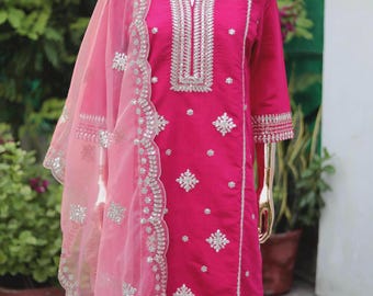 May include: A pink and silver embroidered kurta with a matching pink dupatta. The kurta has a V-neckline and is decorated with silver sequins and beads. The dupatta is sheer and has a scalloped edge.